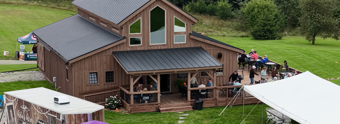A large barn with people gathered on a patio 
